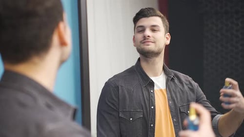 Young Man Sprays Cologne in Mirror Getting Ready