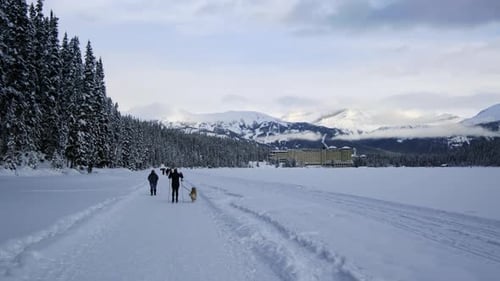 People Skiing Beside The Evergreen Forest With The Mountainous View In Banff National Park. wide sho