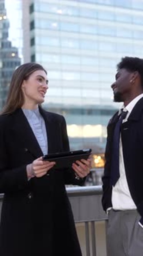 Business Colleagues Discussing Work on a Tablet Outdoors