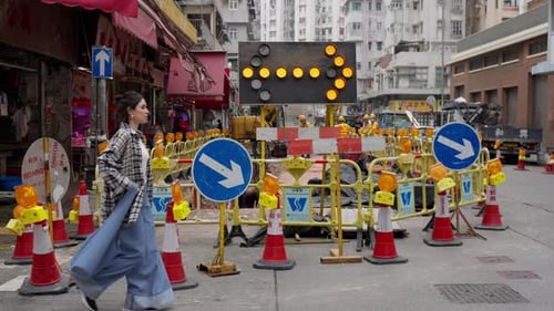 A Girl Walks Against the Background of Road Works Signs