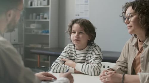 Young Boy and His Mother Talking to Doctor in Medical Office