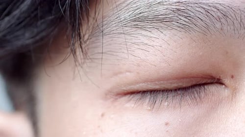 Close up of Asian Man's face. Attractive boy with beautiful eyes. Caucasian young male model with ey
