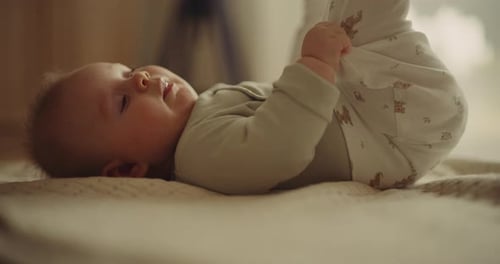 Gros plan du bébé tenant les pieds et souriant