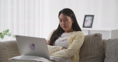 Woman Works on Laptop on Couch at Home