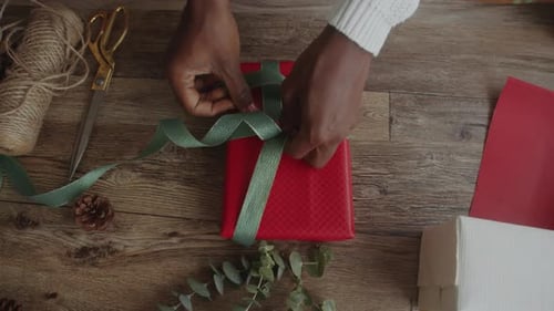Person Decorating Red box with Green Ribbon Making Gift for Christmas