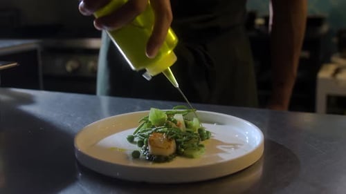 Chef Drizzles Yellow Oil on a Gourmet Dish