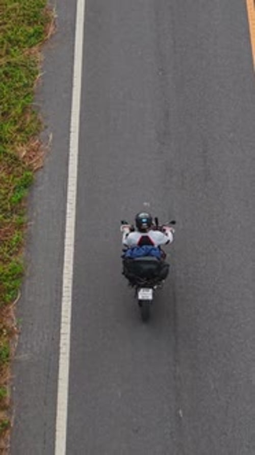 Aerial View of a Motorcyclist Traveling on a Picturesque Rural Road with Changing Perspectives
