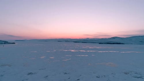 Aerial Over the Frozen Baikal at Beautiful Pink Orange Sunrise Sun Reflections on the Ice Winter