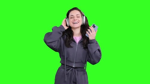 Lächelnde junge Dame, die Musik mit Kopfhörern auf dem Chroma Key hört