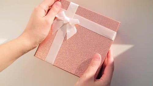 Close Up of Female Hands Showing a Pink Gift with White Ribbon Girl Opens the Gift Focus on the Box
