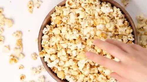 Popcorn Tossed in a Wooden Bowl on a White Background Slow Motion Video Close Up Top View