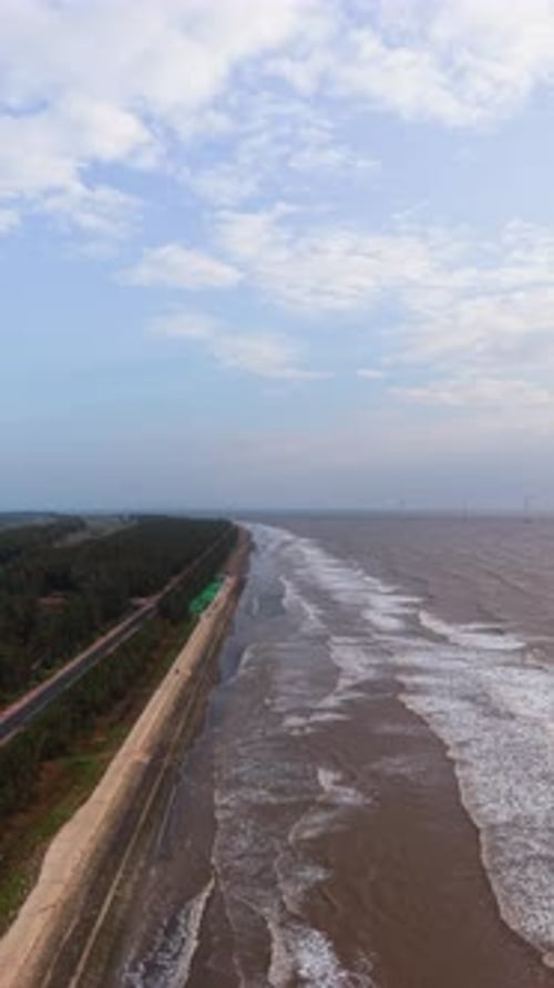 Waves roll into Tra Vinh beach while the sun shines in the sky over the sandy shore.