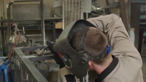 Welder Joining Metal with Bright Sparks in Workshop