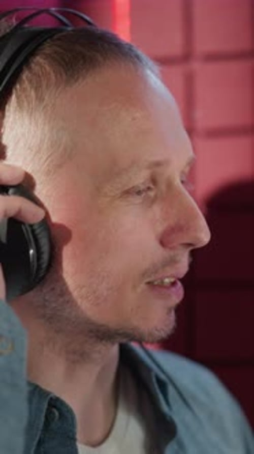 Man Adjusting Headphones in Recording Studio with Acoustic Panel Background