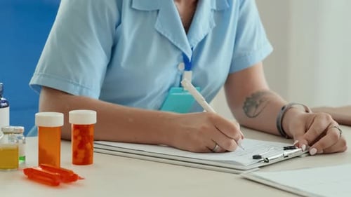 Joven médico generalista tomando notas en un documento por lugar de trabajo