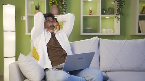 Bored and stressed young man at what he sees on laptop.
