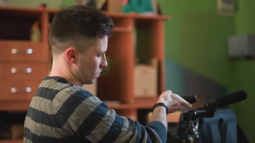 Man Adjusting Video Camera with Microphone in Creative Home Studio