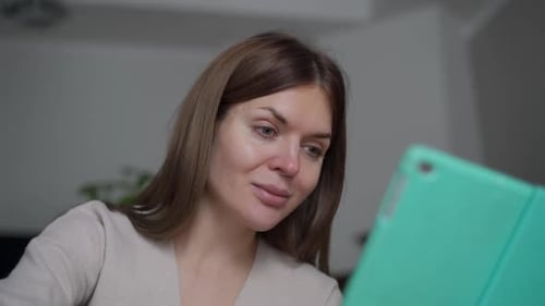 Young Woman Looks at Tablet Indoors During Day