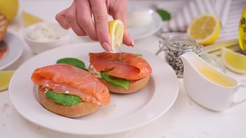 Woman Squeezing Lemon Juice over Salmon Bagel