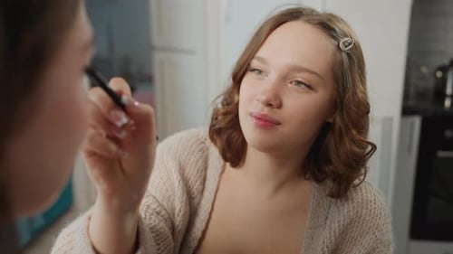 Woman Applies Makeup to Another in Home Bathroom