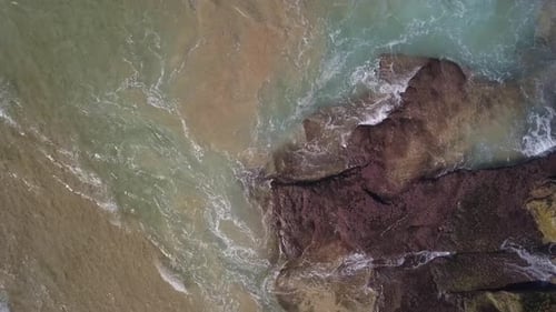 Aerial top down view of ocean wave foaming and splashing from above rolling and breaking on empty oc