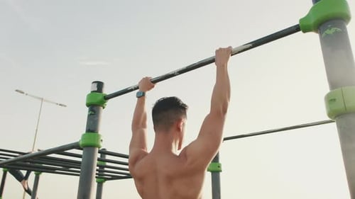 Shirtless Man Exercising on Outdoor Fitness Equipment