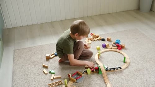 Child Plays with Wooden Toy Train Set Indoors