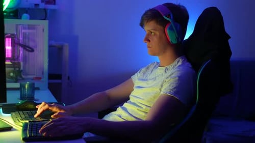 Side View of Happy Professional Male Gamer Wearing Gaming Headset Having Fun Playing Online Video