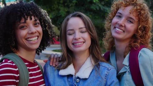 Três jovens estudantes universitárias sorrindo juntas para a câmera no campus