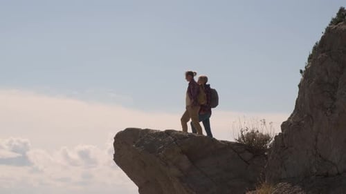 Two Hikers Walking on a Rocky Cliff