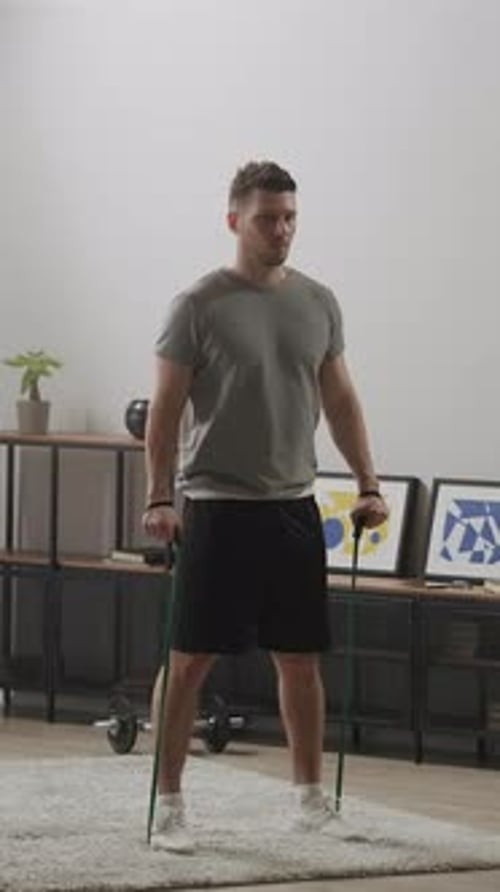 Focused Man Exercising with Resistance Bands During Home Workout Session in Modern Living Room