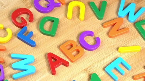 Colorful ABC Alphabet letters rotate on a wooden background. The concept of learning, school