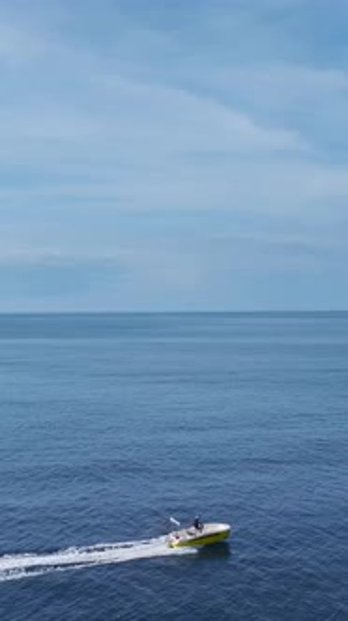 Vertical Video of a Speedboat Cutting Through the Azure Sea With White Waves Splashing Under a