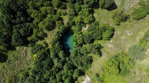 Aerial hight footage rotating around lake with turquoise water located in a mountain valley with