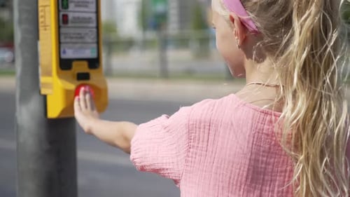 Menina com rabo de cavalo loiro aperta o botão Cross Street em pé na calçada Garota cruza a estrada