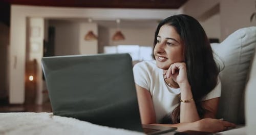 Woman, thinking and happy with laptop on couch, home or research for article