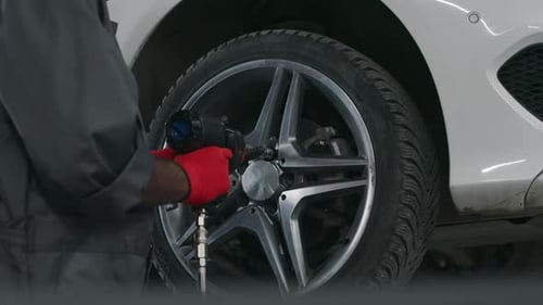Anonymous Car Technician Tightening Bolts on Wheel with Electric Wrench
