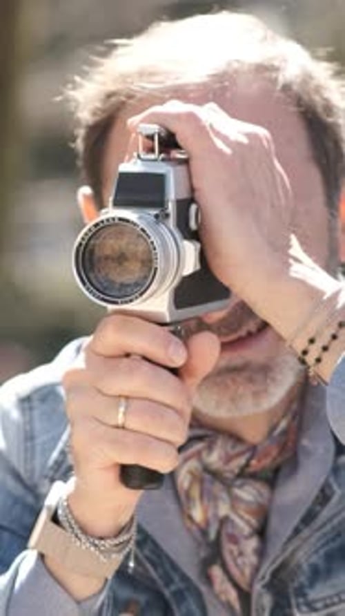 Reifer Mann dreht Video im Stadtpark mit vertikalem Vintage-Kamera-Filmmaterial