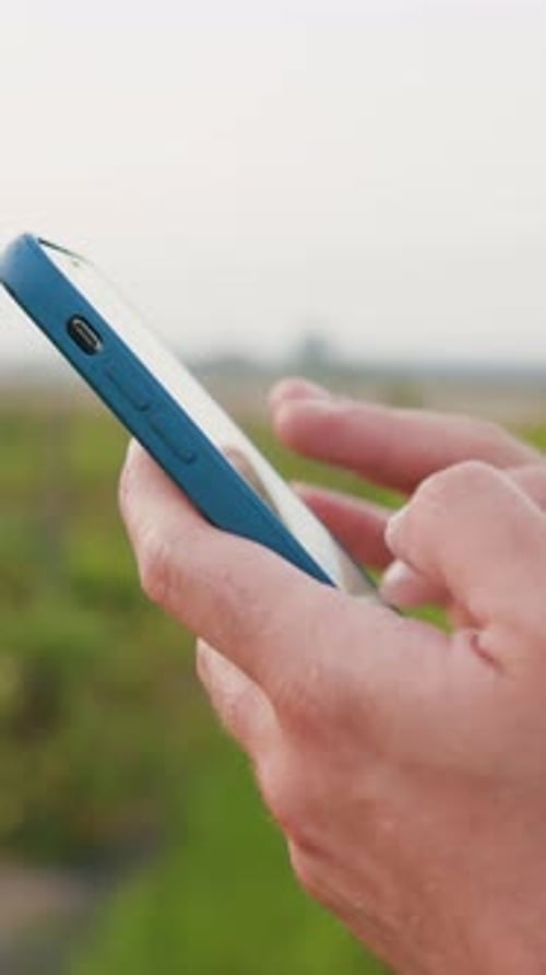 Close Up of Farmers Hands Using Smartphone and Searches for Information in Mobile Phone in