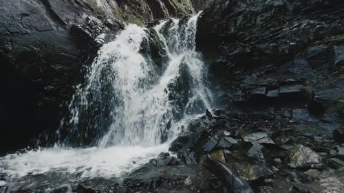 Cascading Waterfall Over Rocks in a Mountainous Landscape