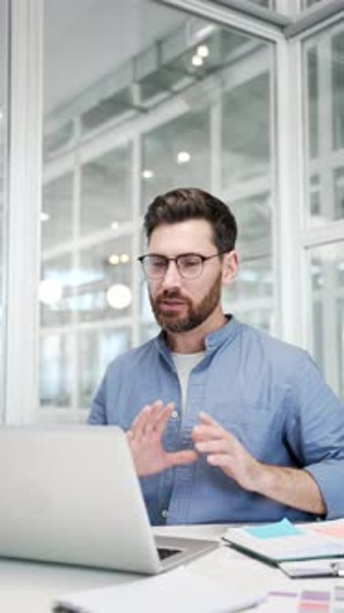 Confident businessman talking on video call using a laptop computer sitting at workplace in a office