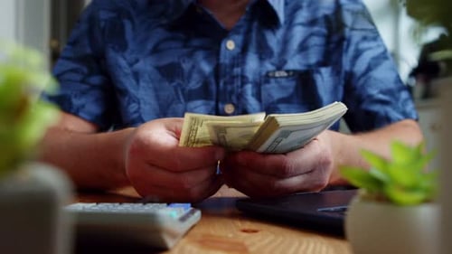 Man Counting Stack of Cash at Desk