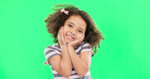 Happy, girl face and green screen with smile of cute innocent child isolated against a studio