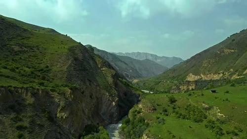 Serene River Flowing Through Green Valley Encircled By Mountains and GrassCovered Hills