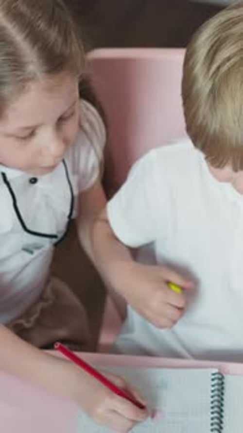 Children Drawing Together at a Table Indoors