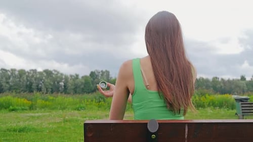 Woman Afraid to Insert Glucose Sensor in Arm Sitting Outdoors in Park