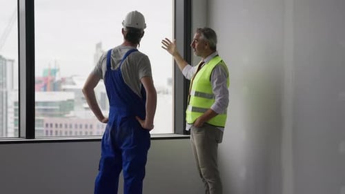 Engineer Contractor Working with Young Electrician on New Building