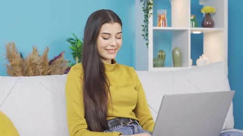 Smiling Woman Using Laptop on Couch at Home