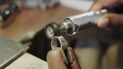 Biracial female worker shaping ring using handcraft tools in workshop in slow motion