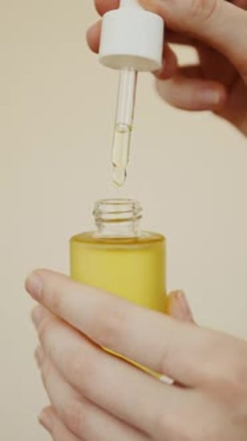 Dropper Drips Liquid Into Yellow Bottle Close Up